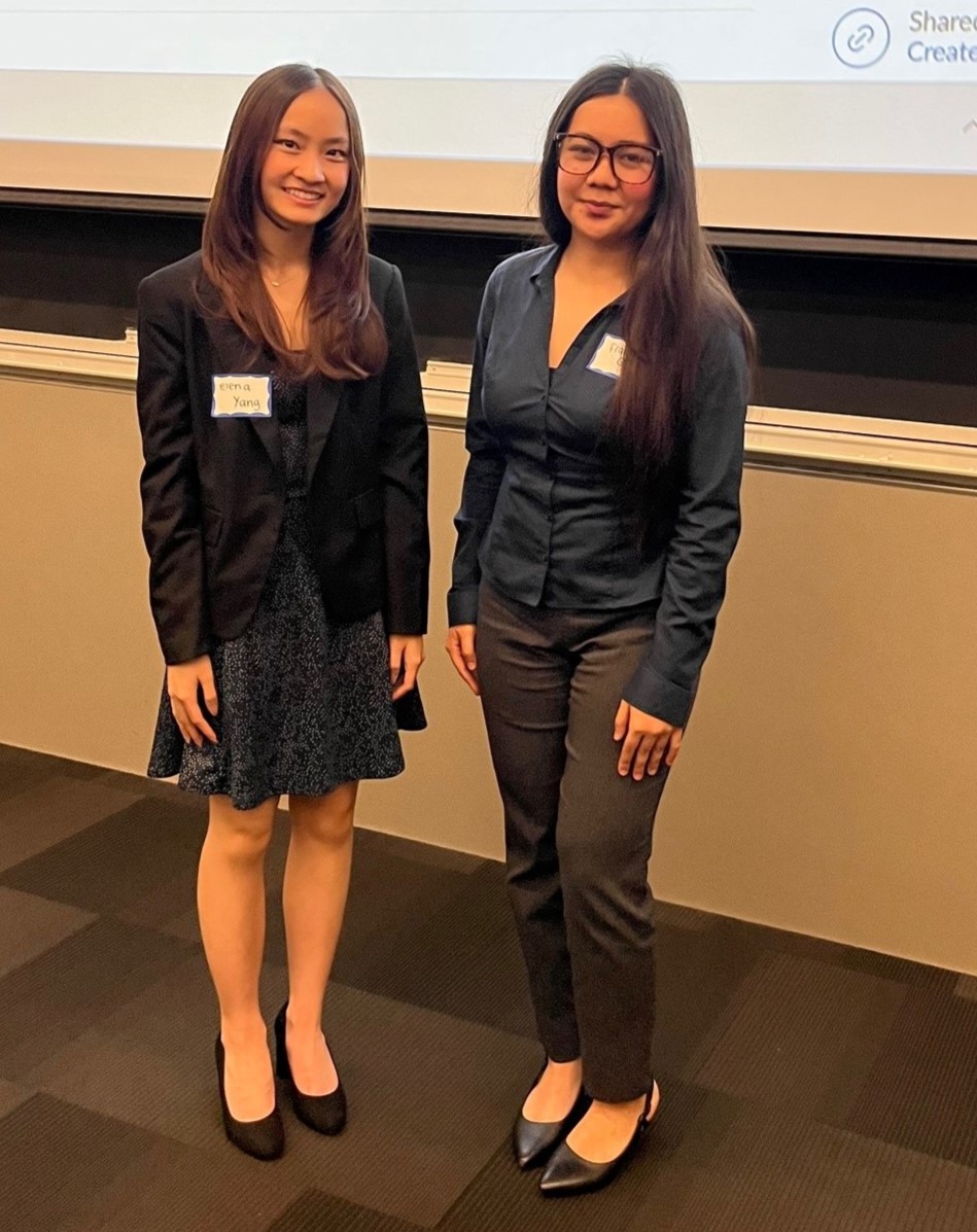 Two female students pose for a photo at a conference.