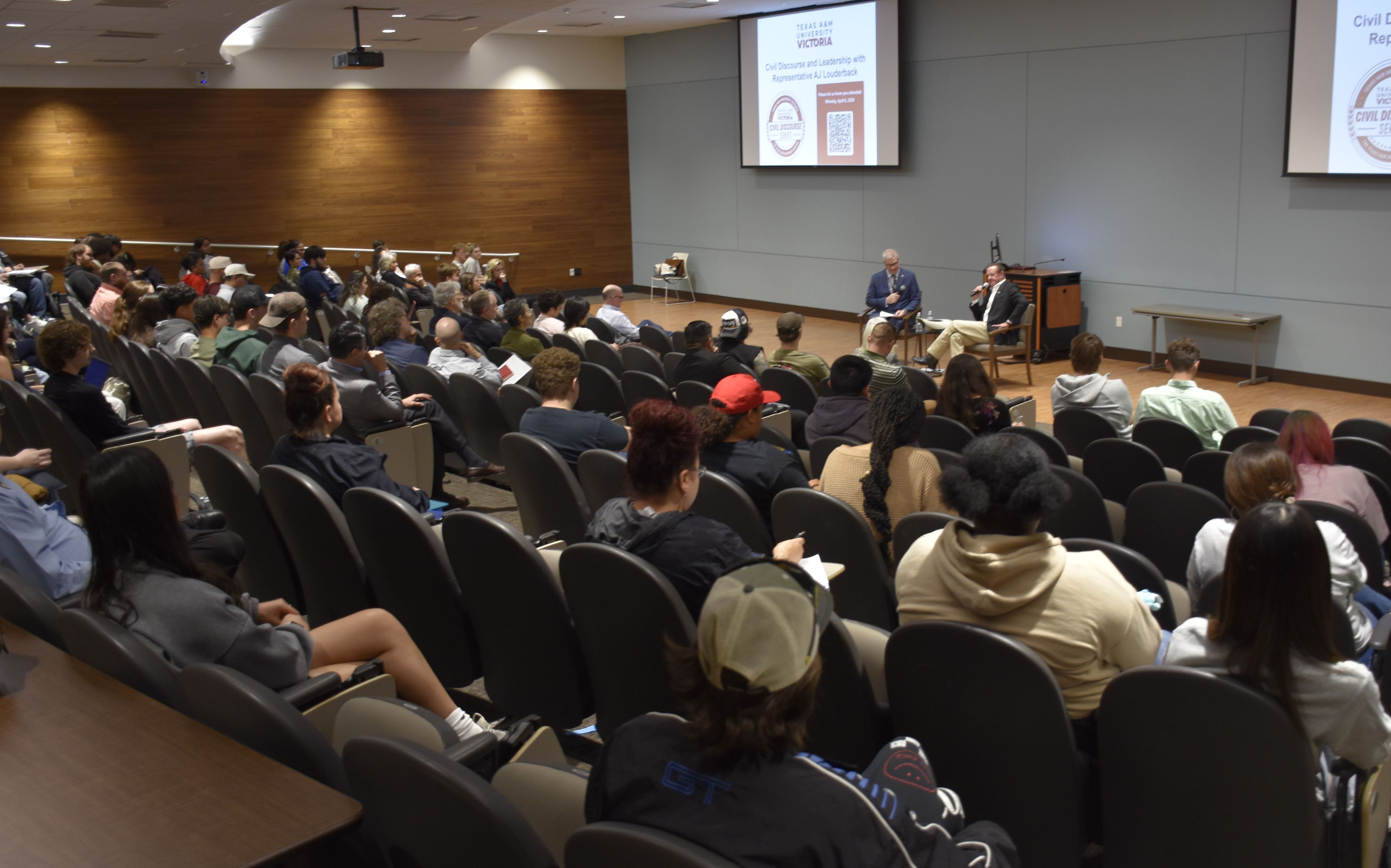 AJ Louderback and Woodrow Wagner speak to an auditorium full of students.