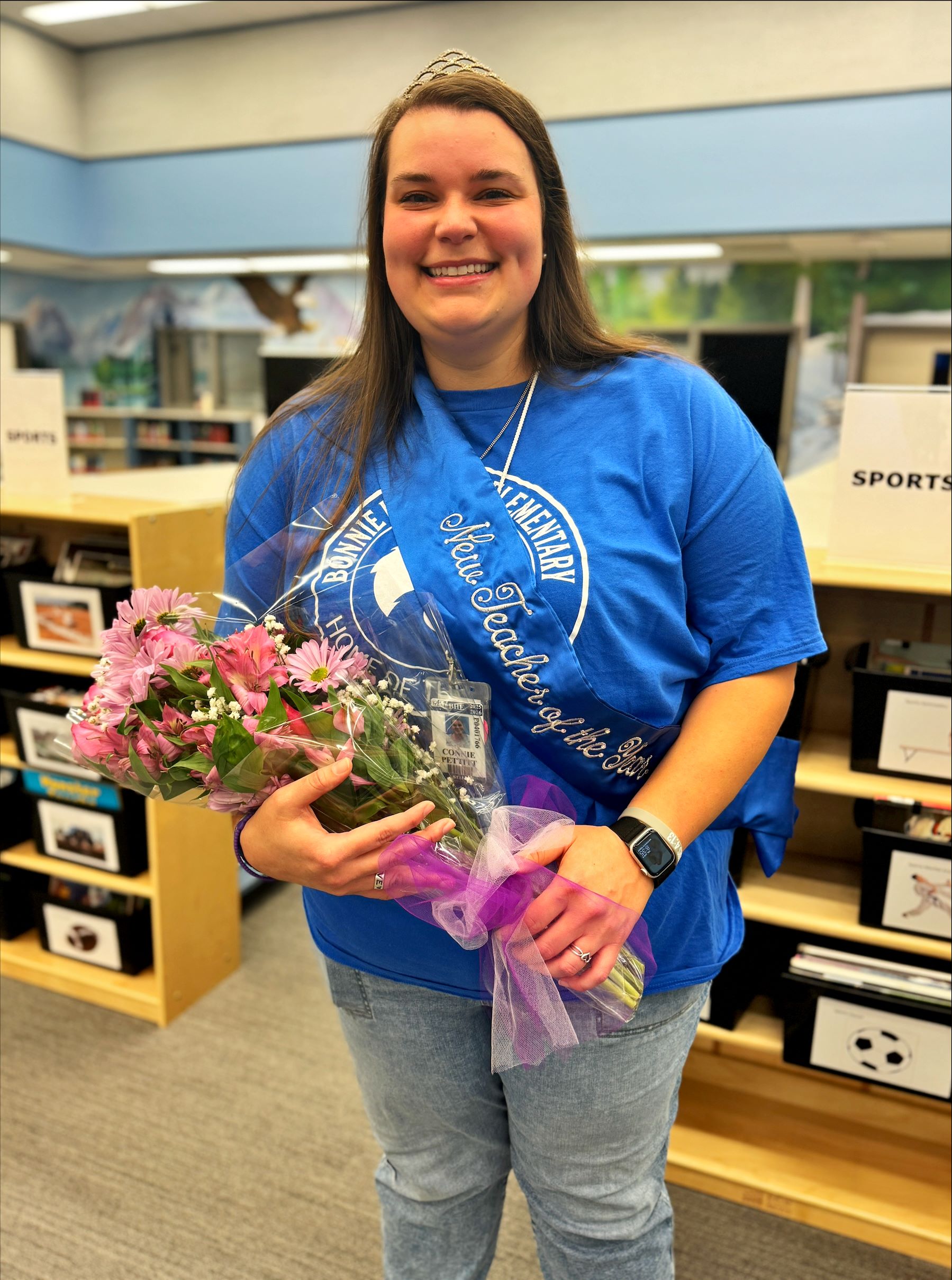 Connie Pettitt holds flowers and wears a tiara and a sash that says New Teacher of the Year.