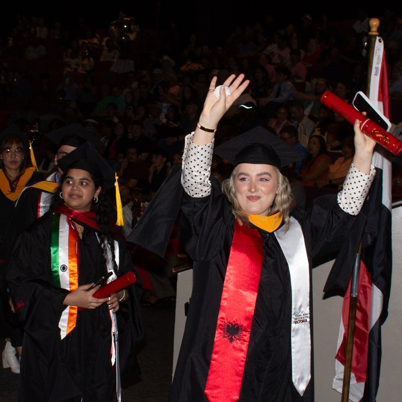 A graduate holds her hands up in celebration.