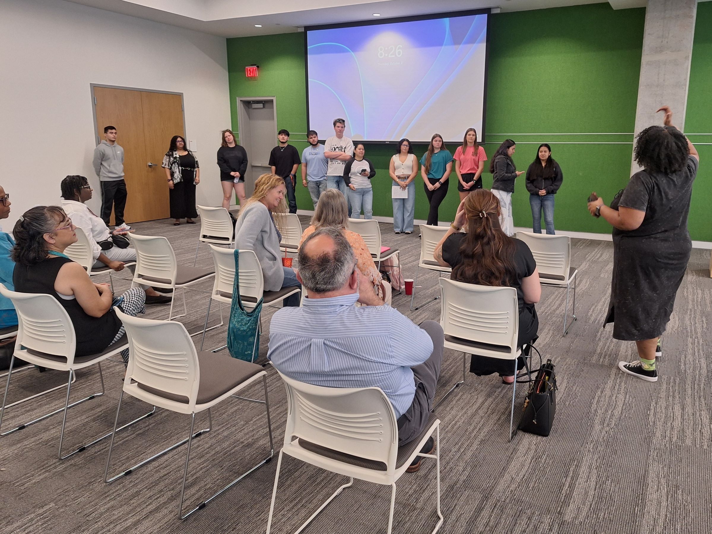 A group of college students stand in front of a room full of adults.